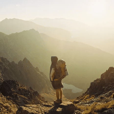 A person with a backpack is standing on the side of a mountain.